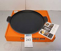 Top view of griddle showing black cooking surface, side handles, booklet and box