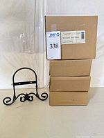 Four sealed Longaberger boxes stacked with one wrought iron easel displayed in front