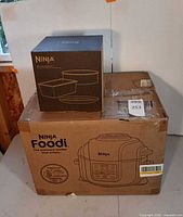 Sealed retail box of Ninja Foodi cooker and separate boxed Deluxe Bake Kit