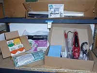 Overview of lot with Haan steamer in open box, Space Bag packaging, Scrub Daddy cartons, Campanelli set