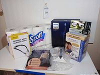 All items grouped on table: Sonicare box, Scott tissue rolls, LifeSource BP monitor box, neck light package, lens cleaner boxes, compression sleeve, defuzzer
