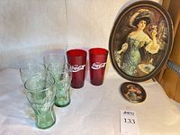 Group shot of 4 Coca-Cola glasses, 2 red tumblers, large oval and small round Pepsi trays