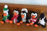 All five Coca-Cola penguin plush displayed on wooden surface