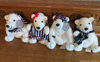 Group shot of four Coca-Cola polar bear plush toys with various accessories