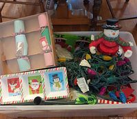 Overall contents inside storage bin showing crackers, serving dish, snowman, string lights