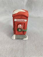 Front view of red porcelain telephone booth with wreath and snow detailing