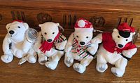 Group shot of four Coca-Cola holiday polar bear plush toys on wooden surface