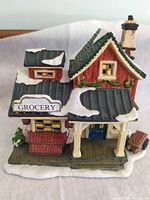 front view showing Grocery sign, porch, sled, snow accents