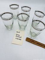 Set of six clear glasses with silver rims shown grouped