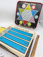 Overview showing Hop Ching Chinese Checkers metal board and stack of Animal Race boards