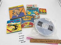 Group shot of all seven film reels and boxes with ruler for scale