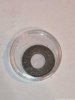 Front view of bronze Indian One Pice coin with center hole in clear plastic capsule