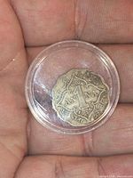 Reverse of 1 Anna coin in holder showing denomination, country and year