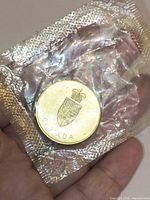 Obverse of sealed gold-tone Canadian medallion in hand