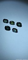 Five oval green sapphires on light background