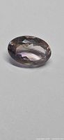 Oval faceted ametrine on neutral background