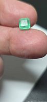Emerald on fingertip showing size and cut