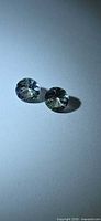 Pair of round faceted Tanzanite gemstones under angled light