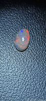 Top view of oval black opal showing red and blue flash