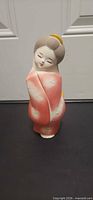 Front view of porcelain figurine showing pink coral kimono and facial features