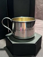 Right-front view of silverplate baby cup showing handle and engraved name