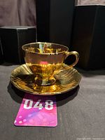Teacup on saucer front view showing gold luster and handle