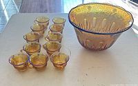 Punch bowl with twelve matching carnival glass cups on table