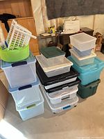 Stacked clear plastic totes with various colored lids, green tub and white basket on top