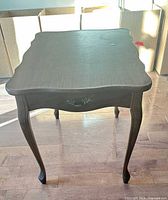 Top and front view of dark brown veneer side table showing scalloped edges and faux drawer front