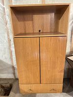 Front view of closed entertainment center showing overall design, open upper shelf, cabinet doors, bottom drawer