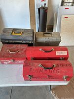 Front view of five toolboxes: three red metal, one black plastic, one tan plastic