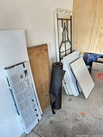 All items leaning against wall: underlayment roll, tables, panels