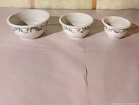 All three nested-size white bowls with green ivy pattern displayed side by side