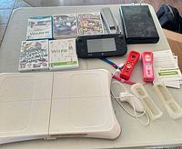 All components laid out including console, GamePad, balance board, remotes, accessories and games