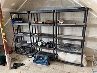 Three black plastic shelving units side by side, filled with miscellaneous items
