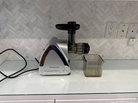 Left-side view of juicer showing power cord, housing, and juice cup