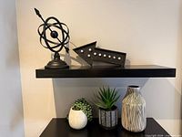 overview of shelf with atom sculpture, arrow accent, two planters and tall vase