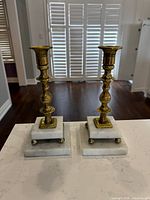 Front view of both brass candlesticks on marble bases
