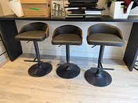 Front view of three matching black faux leather adjustable bar stools