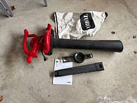 Blower with tube, collection bag, nozzle, adaptor ring and manual laid out on floor