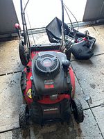 Top view of Benchmark BM2050E 22-inch lawnmower with grass catcher, battery and charger visible
