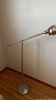 Full view of chrome floor lamp standing on hardwood floor
