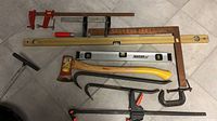 All items laid out: clamps, crowbars, levels, square, hatchet, T-handle tool