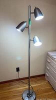 Full view of brushed nickel floor lamp illuminated
