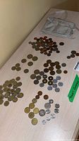 Overview of multiple piles of assorted coins and travel body wallet on tabletop