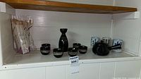 full set on shelf: sake carafe, six cups, teapot, three mugs, chopsticks pack