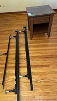 Nightstand next to disassembled adjustable bed frame rails on floor