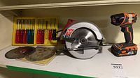 Overview of circular saw, flashlight, screwdrivers and blades on shelf
