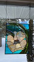 Full view of stained glass panel hanging, showing waterlily design and chain