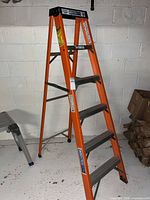 Front view of orange fiberglass 6-ft step ladder with five steps